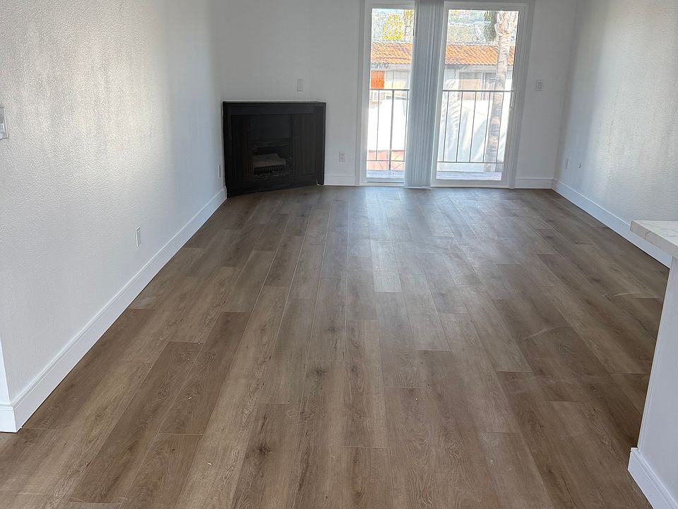 Spacious living room with fireplace and balcony. Hardwood look LVT flooring.