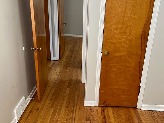view from bedroom 1 across the hall to bedroom 2 (refinished wood floors in both)