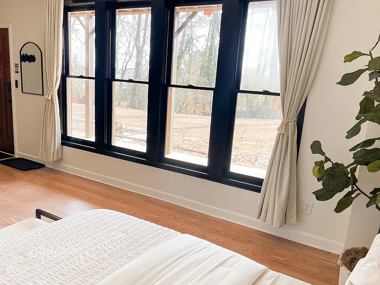Large bedroom windows provide abundant natural light, with blackout curtains for privacy and restful sleep.