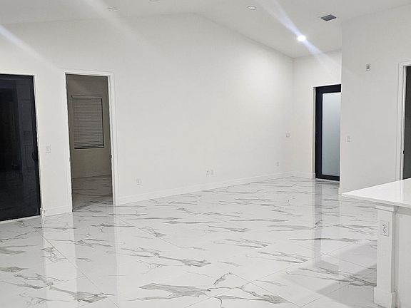 Spacious Open-Concept Living Area with High Ceilings, Recessed Lighting, and Elegant Marble-Look Tile Flooring