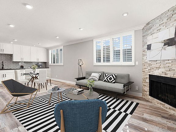 Hardwood floored living room with large windows and stone-accented fireplace.