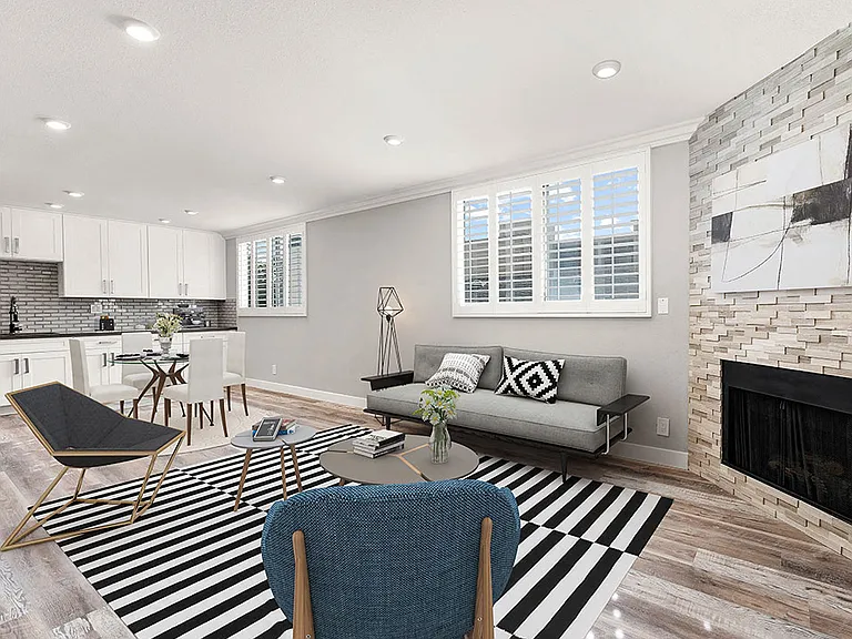 Hardwood floored living room with large windows and stone-accented fireplace.