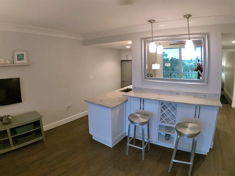 Eat at bar with custom wine rack, cocktail glasses in cabinets below, two swivel stools with overhead variable lighting.
