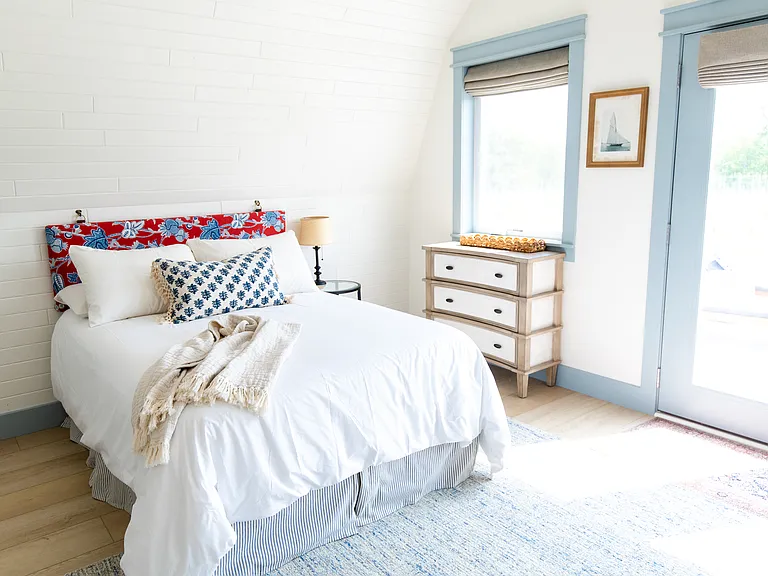 The second bedroom includes two full beds, two small dressers, a closet, a desk, and French doors that open out to the expansive back deck that overlooks vineyards.