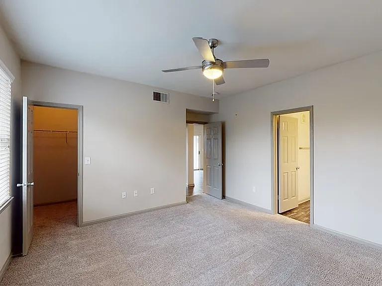 Spacious apartment bedroom with large closet and plush carpet flooring.