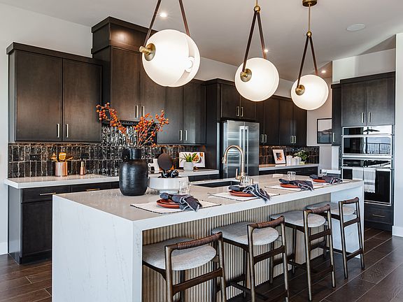 A modern and spacious kitchen with dark wood cabinets, a large white island with bar stools, and thr