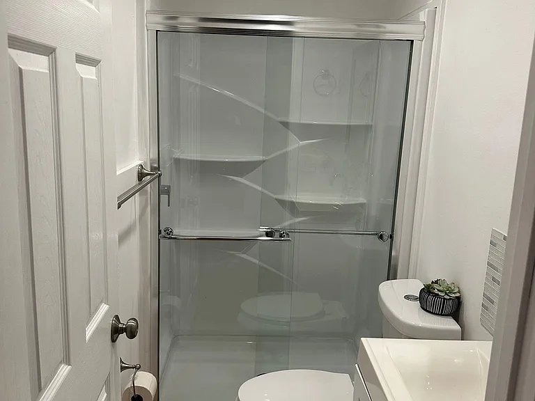 Well-appointed bathroom equipped with a toilet, shower, mirror, and storage cabinet