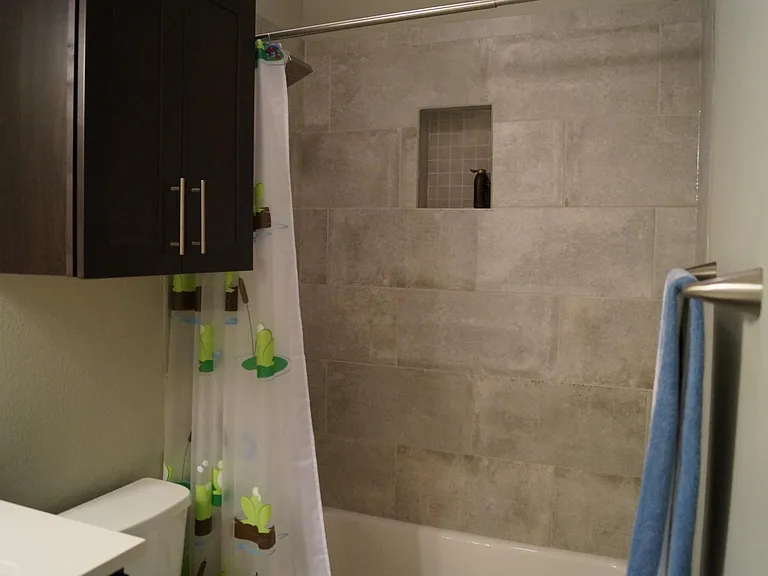 Upstairs full bathroom (view #3). Stone countertops and elongated toilet