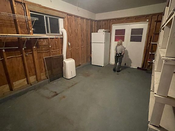 Enclosed garage is laundry room, not heated and cooled, with shelving for storage