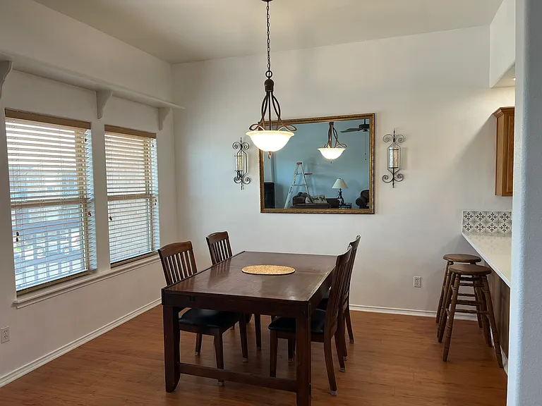 Dining area with natural lighting. Table seats four with two bar-stools for the breakfast bar.