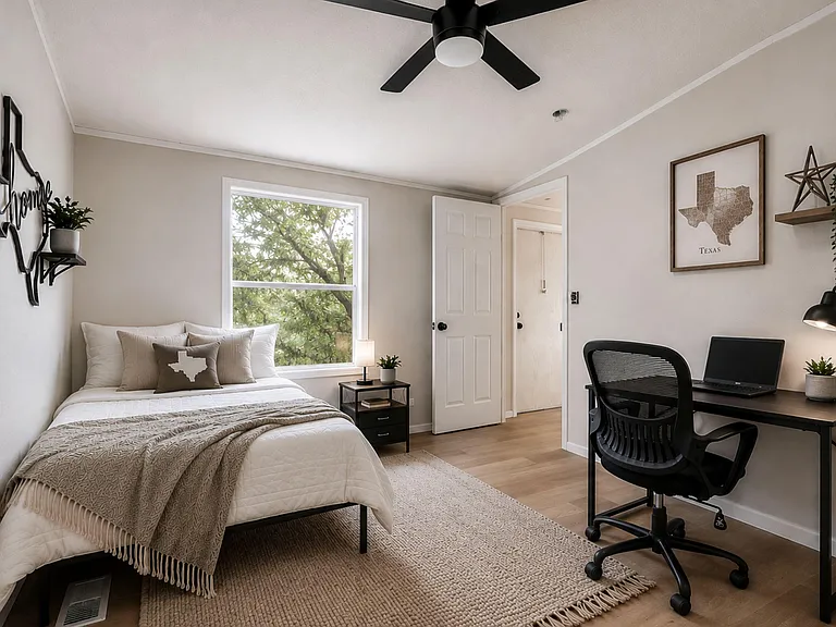 Staged bedroom with a full bed, ceiling fan, large window, and dedicated desk setup for work or study.