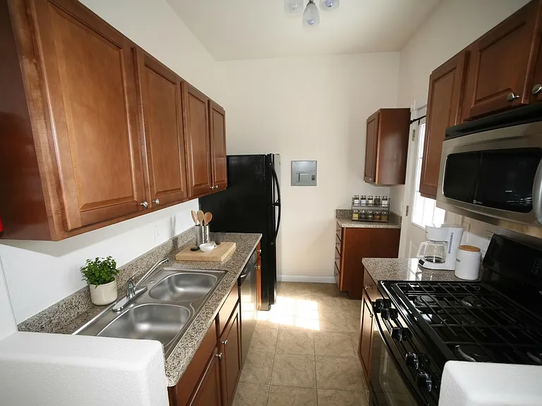 Separated kitchen layout with cherry cupboards and a gas stove. Step straight out onto your private east-facing balcony_perfect for enjoying your morning coffee in the sun! :)
