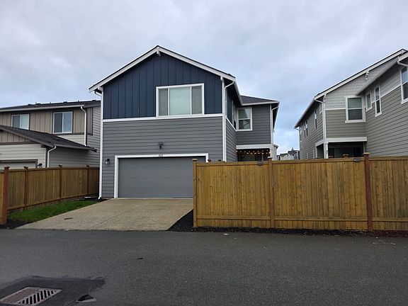 Back side of the house with garage pathway and the lawn