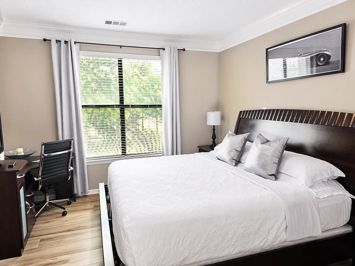 Relax in a spacious bedroom with a king-size bed, walk-in closet, flat-screen TV, and a functional workspace_ideal for remote work or study. - 401 16th St NW #1271