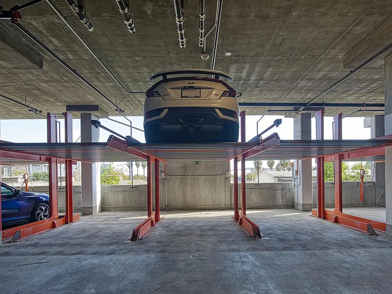 Parking area with an advanced lift system, controlled access, and charging stations for electric cars.