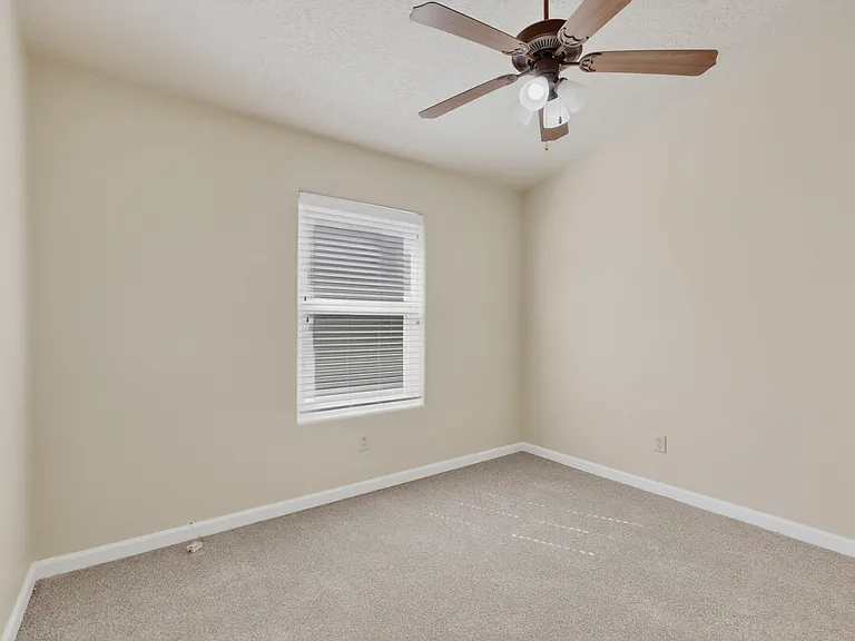 Bedroom #1 features a full closet with bypass doors, a window with blinds for natural light, a ceiling fan for great airflow and the vaulted ceilings for a spacious feel.