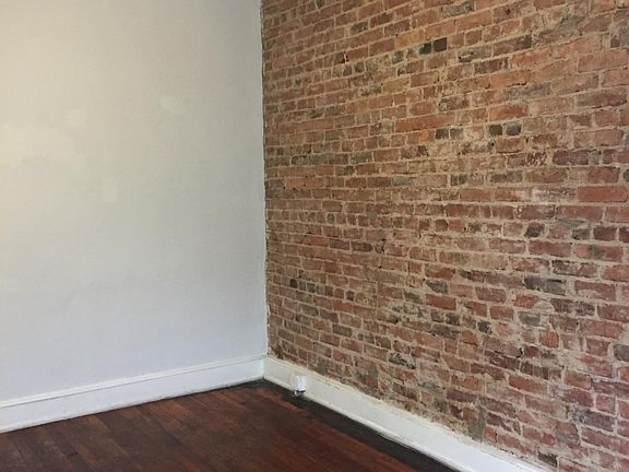 Large Living room is at the front of the apartment - sunlit with hardwood floors and brick wall reveal.