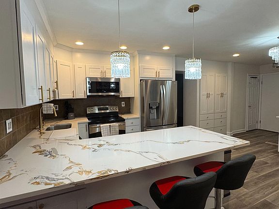 Updated kitchen with a large peninsula for seating, ample white cabinetry, and stainless steel appliances for everyday cookin