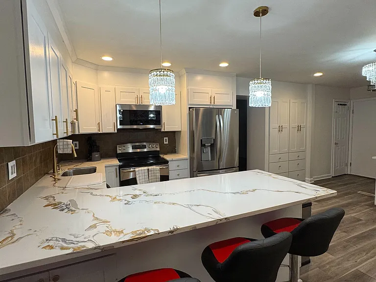 Updated kitchen with a large peninsula for seating, ample white cabinetry, and stainless steel appliances for everyday cookin
