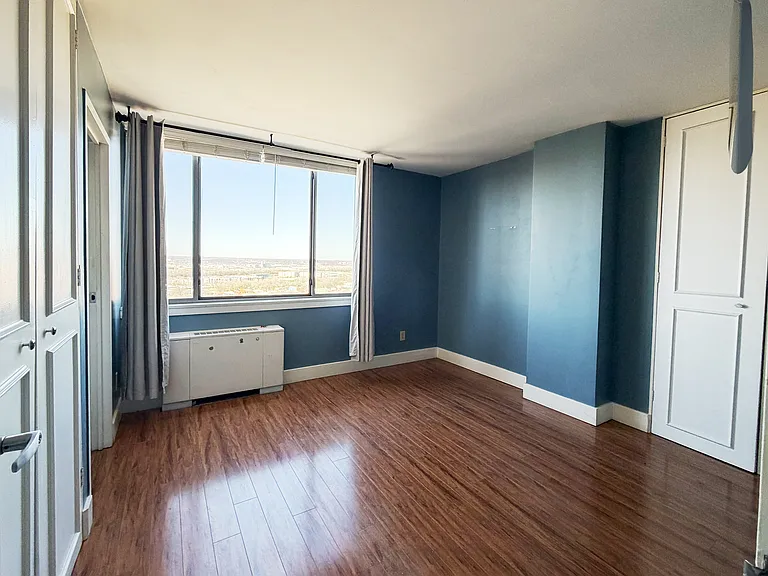 Generously sized primary bedroom with hardwood floors and ample storage