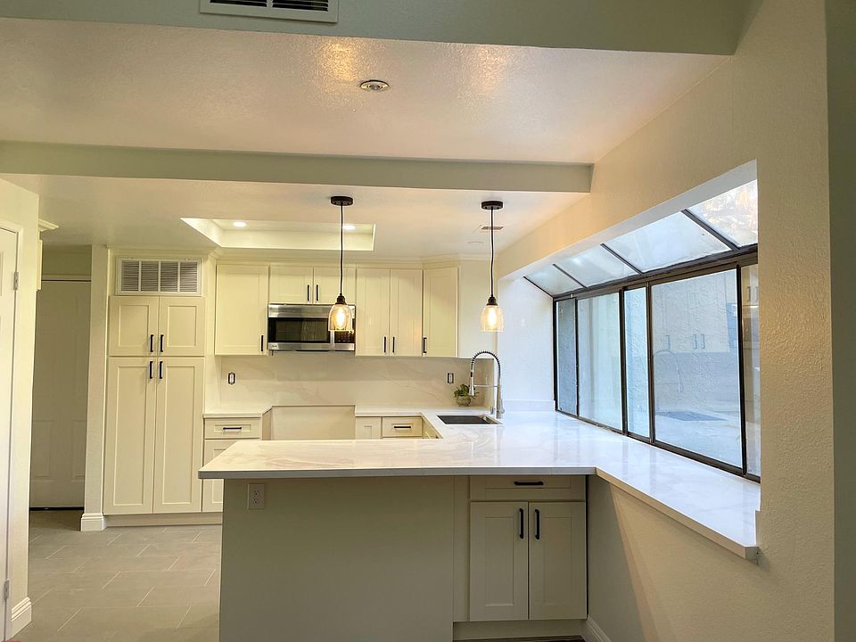 The new kitchen includes quartz counter tops, white cabinets, chic light fixtures, stainless steel appliances (stove, dishwasher, microwave, and refrigerator.)