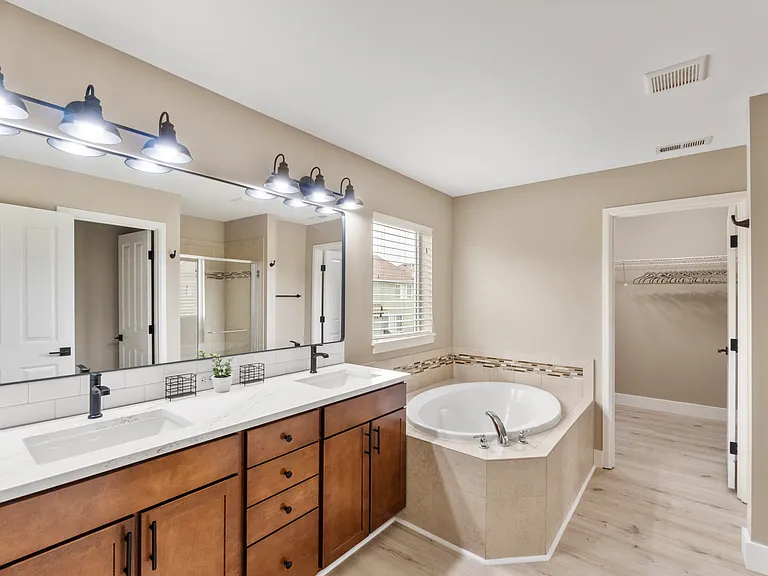 Primary Bathroom features dual sinks, soaking tub, walk-in shower, and toilet, along with an attached walk-in closet
