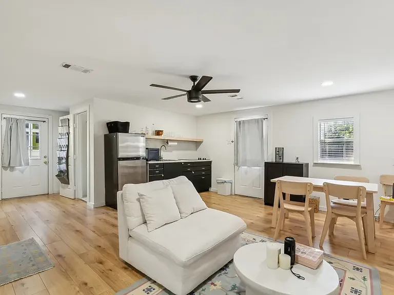 View of studio apartment including living area and kitchenette looking back to front door and entrance to bathroom.