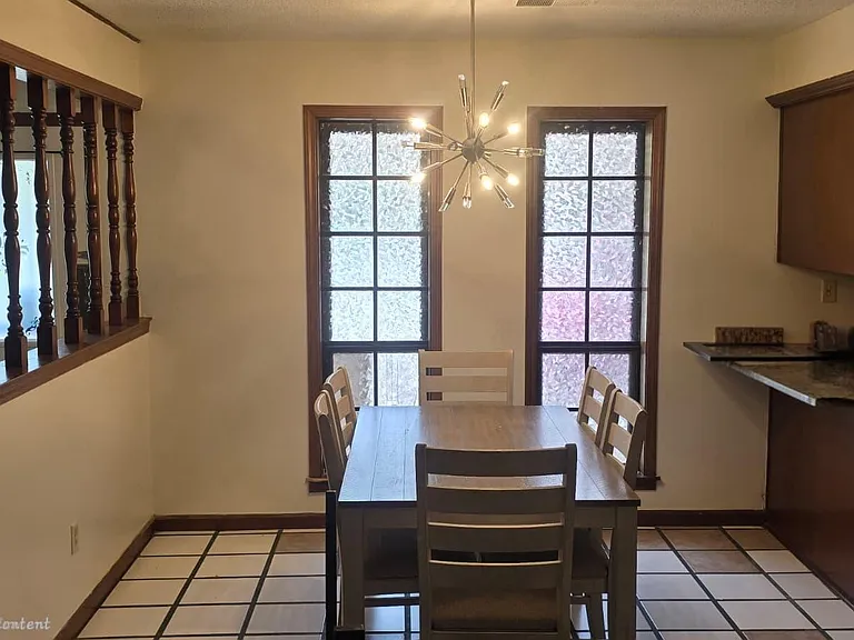 Eat-in dining area with a table set for four, two tall windows, and convenient pass-through from the kitchen.