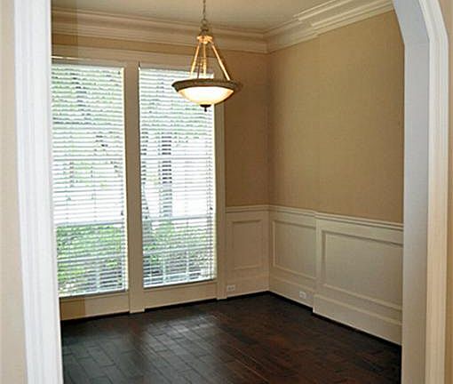 The formal dining room features wood flooring, crown molding and a detailed wainscot -- an elegant t