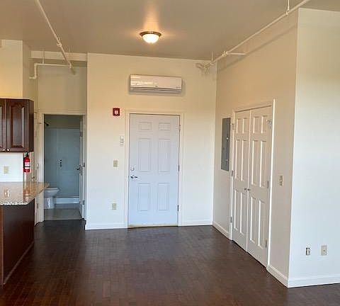 Living room facing entry, closet to right. Central HVAC unit above entry door.