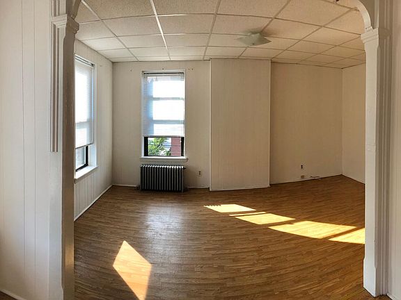Large Bedroom divided in 2 sections like an L shape with brick exposed.