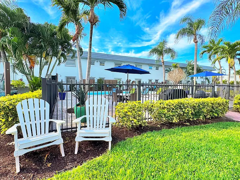 Enjoy the best of outdoor living with cozy Adirondack chairs and lush landscaping.