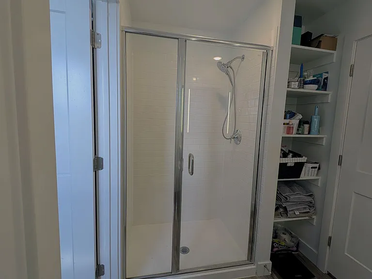 Built-in storage behind bathroom door, walk-in shower