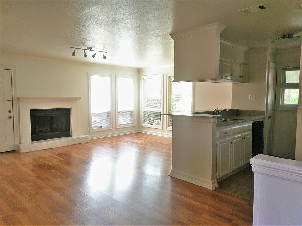 Open living space with the door next to the fireplace leading to a private yard with artificial turf.