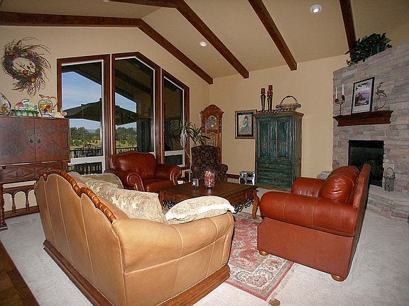 Living room features beamed ceilings, stone fireplace, 