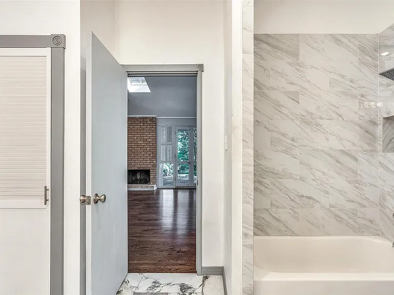 Bathtub with marble-look tile surround and built-in shower niche
