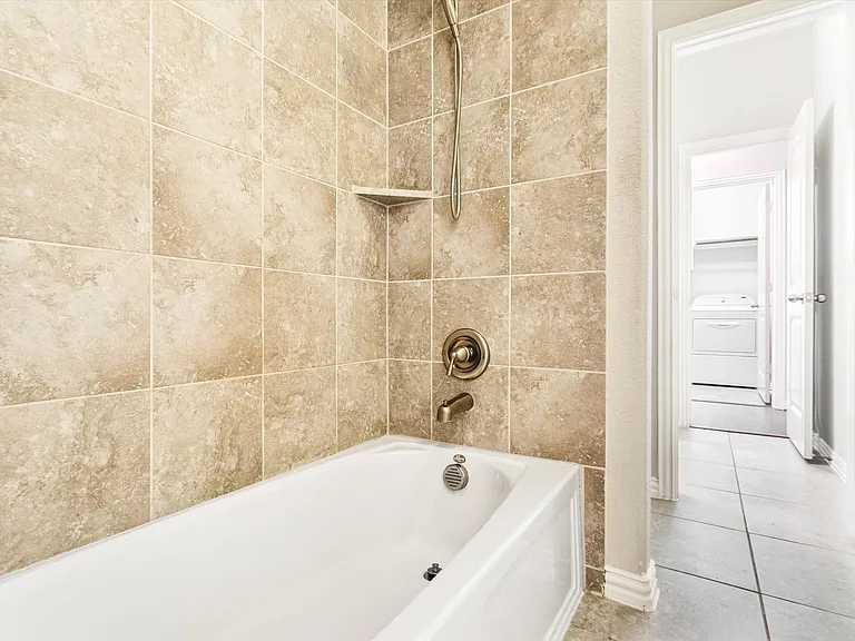 Bathtub and shower combination with bronze-finish fixtures and an integrated corner shelf