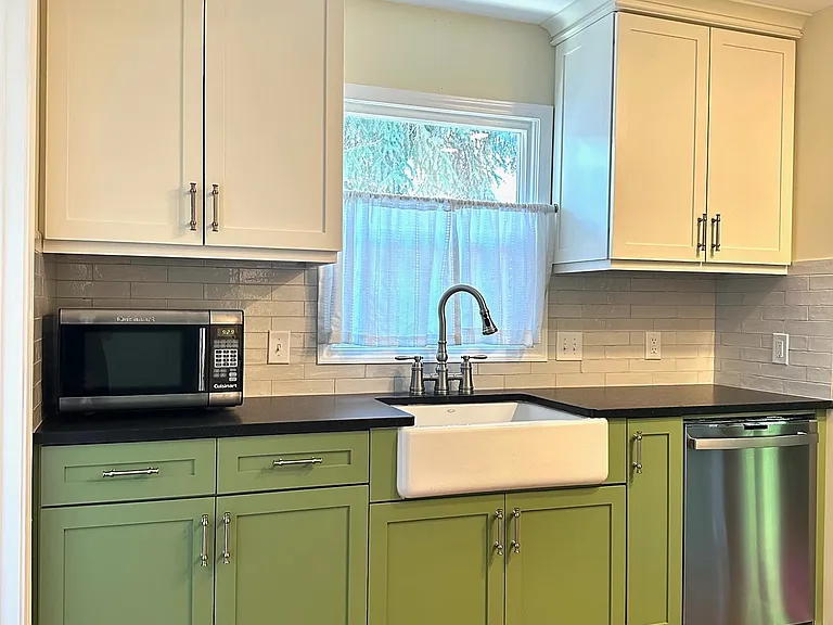 Updated kitchen with granite countertops, custom cabinets, and a large farmhouse sink.