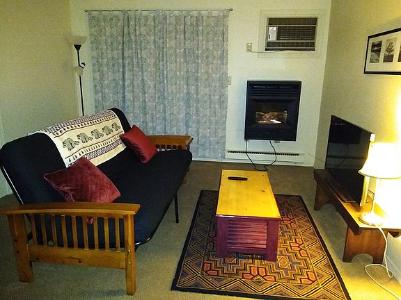 Living room with gas fireplace; balcony entrance beyond curtains