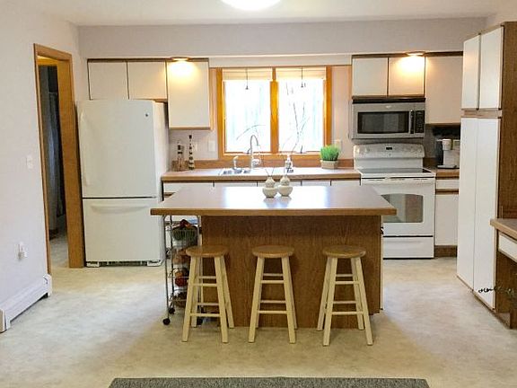 Bright and cheery kitchen with island and desk area - new vinyl flooring and lighting just added - a