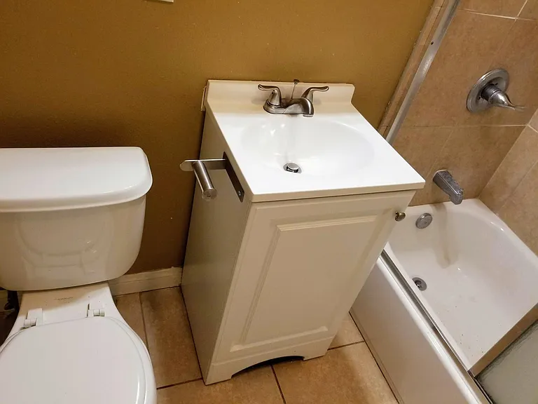 Bathroom with toilet, sink, and full shower with tub