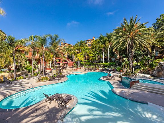 Swimming pool and spa surrounded by lounge chairs.