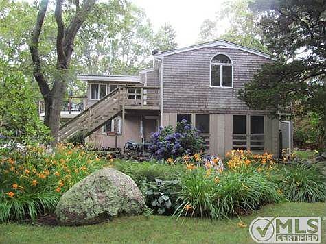 Side view showing the lovely perennial beds, screened-in porch on the first floor, separate stairs for the second-floor master suite and the large deck, just perfect for morning coffee or dinner at sunset.