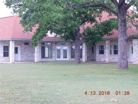 Covered patio with large shade trees and several access to home, mud room, workshop and garage.