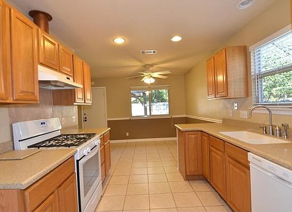 Kitchen with Corian countertops with one piece sink along white appliances.