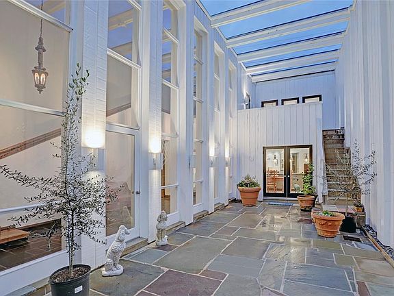 MAIN ATRIUM: Dramatic two story space makes this home like no other. Dramatic floor to ceiling windows, slate stone covered stairs ascend to the balcony of the primary bedroom.