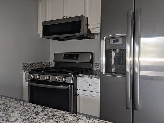 Sleek galley kitchen with NEW stainless steel appliances.