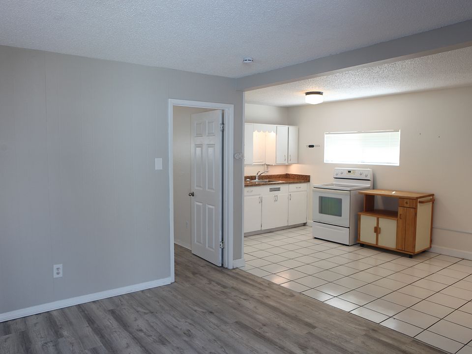 Unit 5 - wide angle view of living room, bedroom doorway, and kitchen