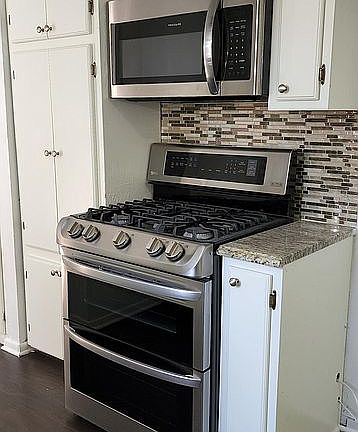 Kitchen with newer double gas oven and built-in microwave oven.
