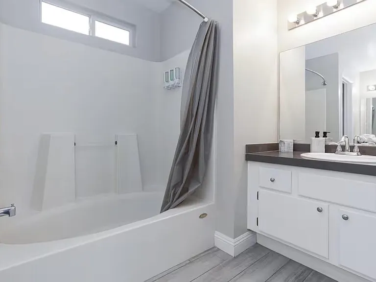 Full bath with tub/shower combo, wide vanity with ample storage, and large mirror with overhead lighting.